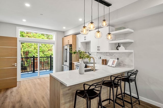 kitchen with high end fridge, kitchen peninsula, white cabinets, and a breakfast bar