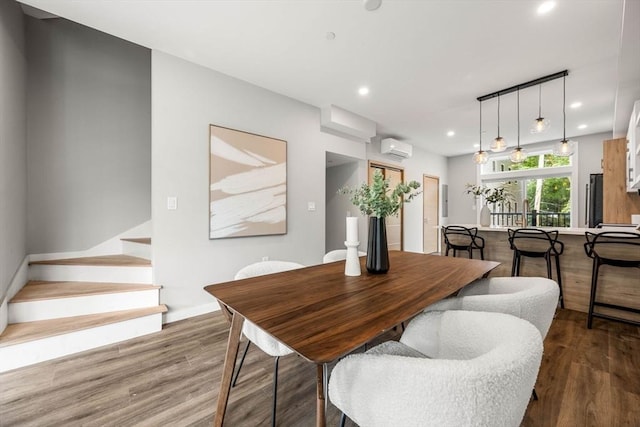 dining space featuring wood-type flooring and a wall mounted air conditioner