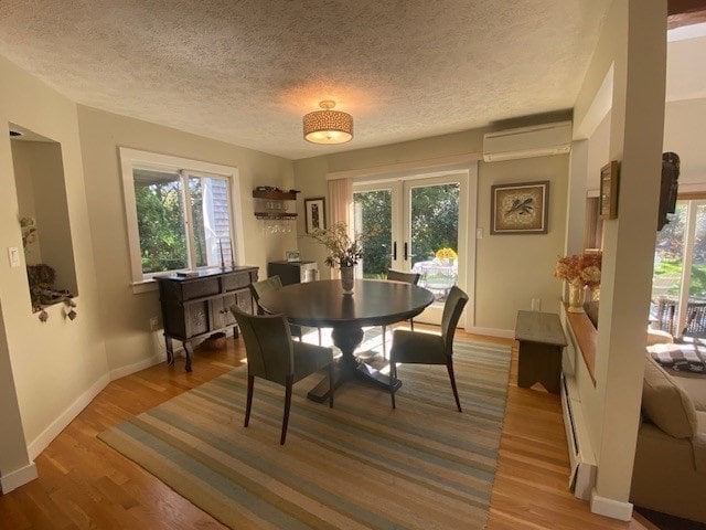 dining room featuring a wall mounted air conditioner, a textured ceiling, hardwood / wood-style flooring, and plenty of natural light