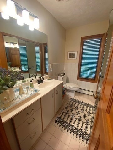 bathroom featuring a baseboard radiator, toilet, tile walls, vanity, and tile patterned flooring