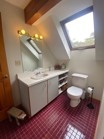 bathroom featuring vanity, toilet, a skylight, and tile patterned flooring