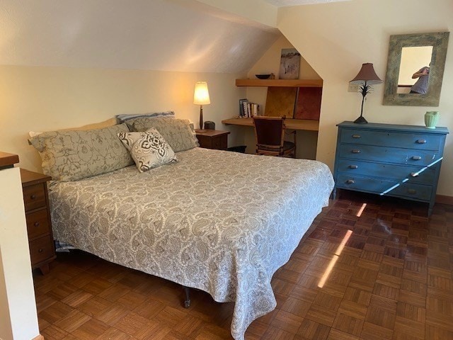 bedroom with vaulted ceiling and dark parquet floors