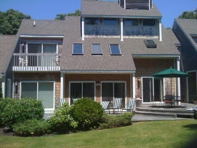 rear view of property with a yard, a patio area, and a balcony