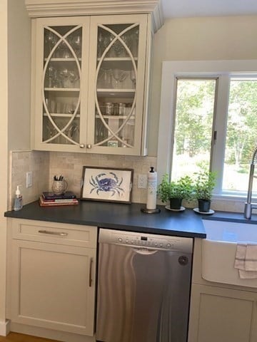 bar with decorative backsplash, a wealth of natural light, stainless steel dishwasher, and white cabinets