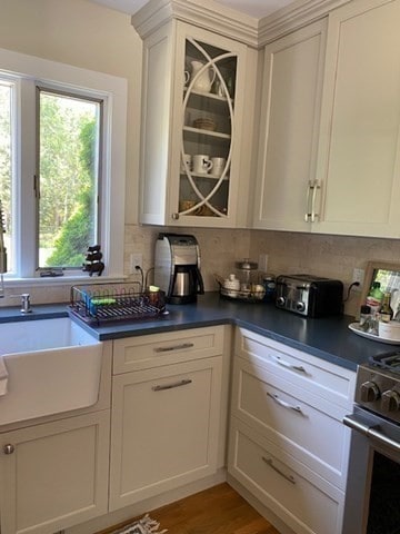 kitchen with light hardwood / wood-style flooring, sink, white cabinetry, stainless steel range oven, and tasteful backsplash