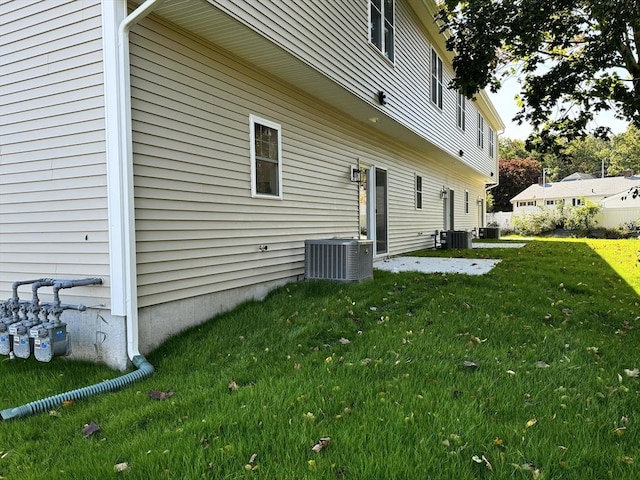 rear view of property featuring central air condition unit and a yard