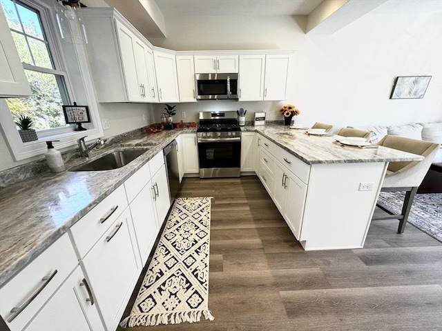 kitchen with a breakfast bar, sink, kitchen peninsula, white cabinetry, and stainless steel appliances