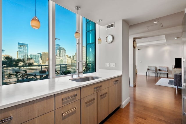 kitchen featuring sink, pendant lighting, light brown cabinets, and hardwood / wood-style flooring