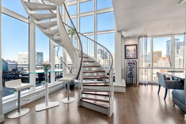 stairway with a wall of windows, hardwood / wood-style flooring, and a wealth of natural light