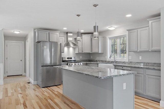 kitchen featuring wall chimney exhaust hood, sink, decorative light fixtures, appliances with stainless steel finishes, and a kitchen island