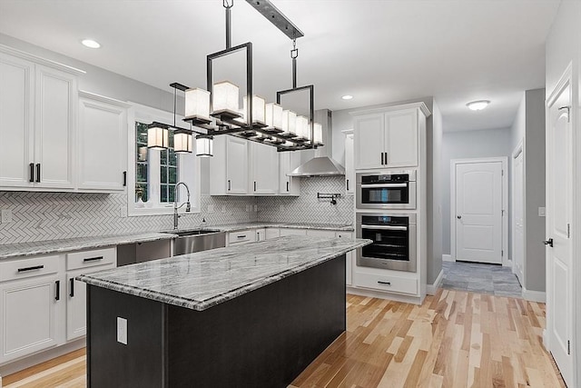 kitchen with sink, backsplash, a center island, light stone countertops, and white cabinets