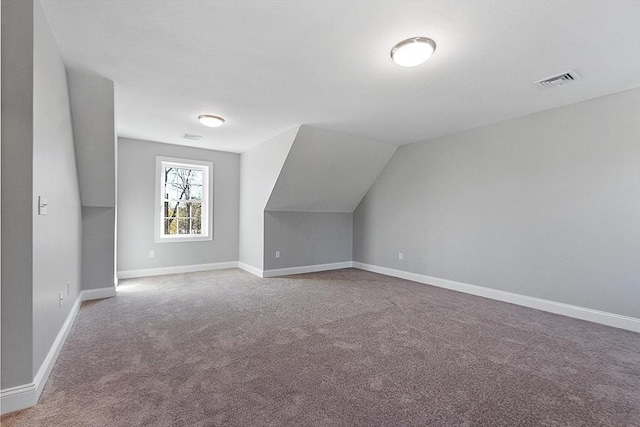 bonus room with vaulted ceiling and carpet floors