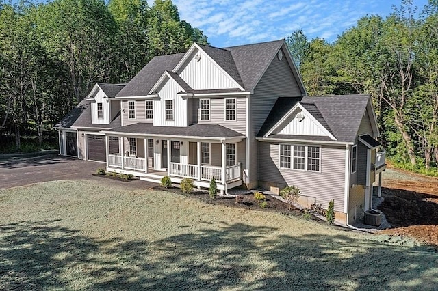 view of front of home with central AC unit, a garage, a front lawn, and covered porch