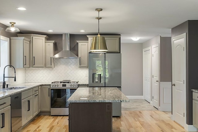 kitchen featuring light wood-type flooring, appliances with stainless steel finishes, sink, and wall chimney range hood