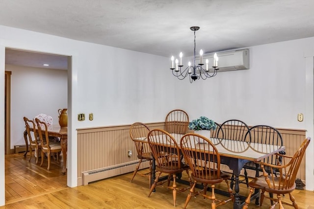 dining space featuring a baseboard heating unit, a chandelier, wood finished floors, and a wall mounted air conditioner