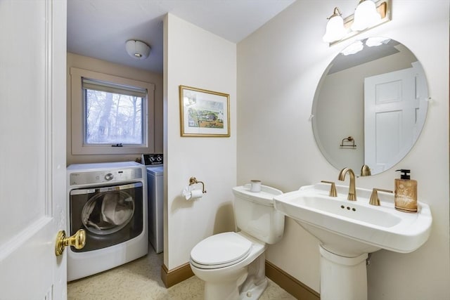 half bath with toilet, washing machine and dryer, and baseboards