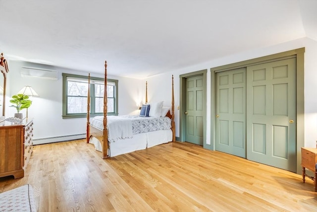 unfurnished bedroom with a wall unit AC, a baseboard radiator, light wood-style flooring, and two closets