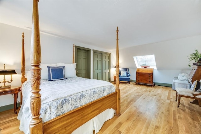 bedroom featuring a skylight, baseboards, and wood finished floors