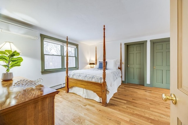 bedroom featuring light wood finished floors, baseboard heating, and a wall mounted air conditioner