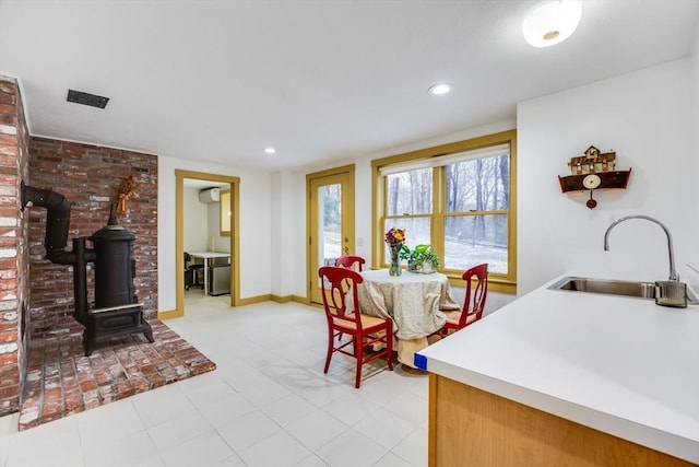 kitchen featuring recessed lighting, a wood stove, light countertops, and a sink