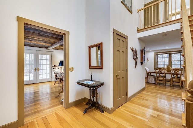 interior space with baseboards, french doors, a high ceiling, and light wood-style floors