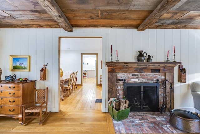 living room with light wood-type flooring, a brick fireplace, wood ceiling, and beamed ceiling