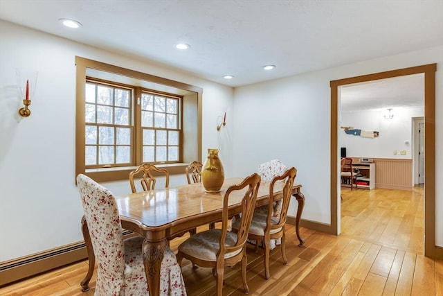 dining area featuring light wood finished floors, baseboard heating, a wainscoted wall, and recessed lighting