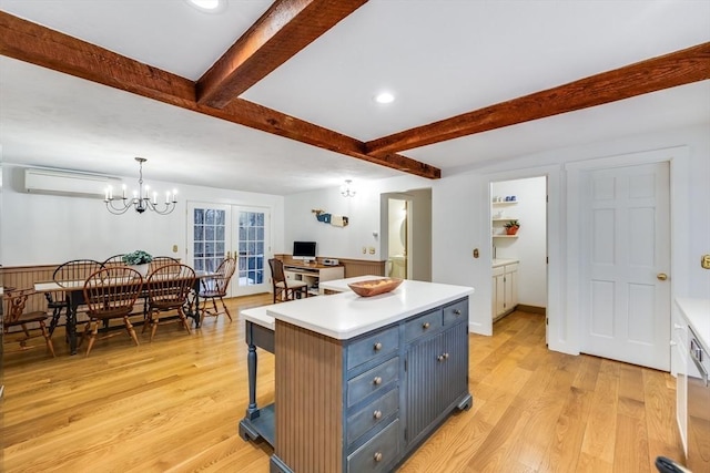 kitchen featuring beamed ceiling, a wall mounted air conditioner, blue cabinets, light countertops, and light wood-type flooring