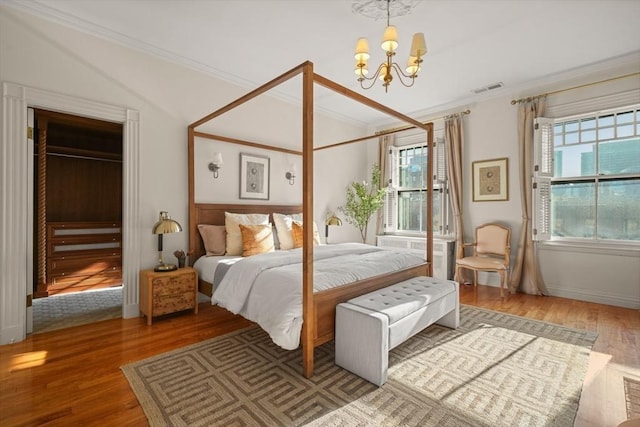 bedroom with wood-type flooring, crown molding, and an inviting chandelier