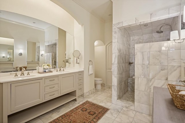 bathroom with toilet, vanity, ornamental molding, and a tile shower