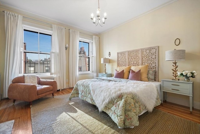 bedroom featuring a chandelier, crown molding, and hardwood / wood-style flooring