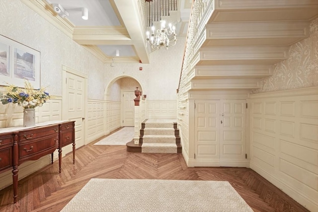 interior space featuring light parquet floors, coffered ceiling, ornamental molding, a chandelier, and beamed ceiling