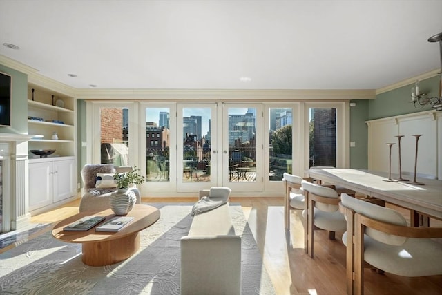 living room with a high end fireplace, light wood-type flooring, built in features, and crown molding