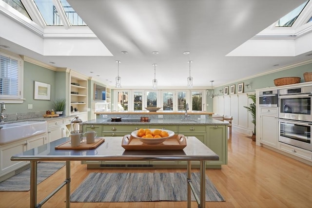 kitchen featuring a center island, sink, a skylight, ornamental molding, and stainless steel double oven