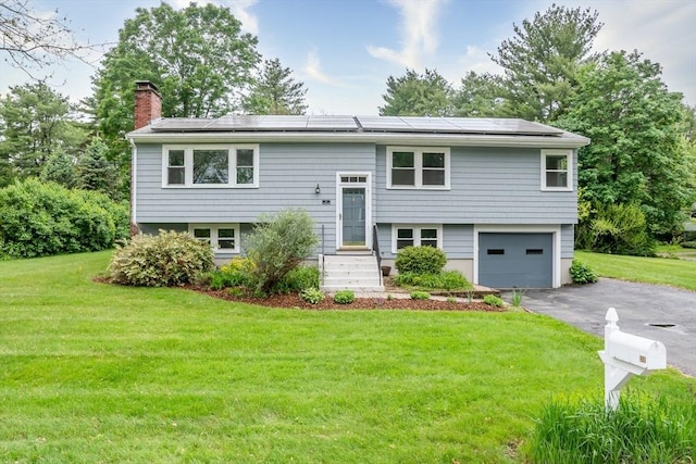 34 Brooks Rd, Wayland, MA 01778 - bi-level home featuring a chimney, a garage, roof mounted solar panels, and a front lawn