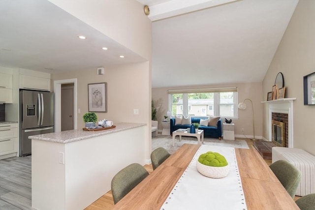 34 Brooks Rd, Wayland, MA 01778 - kitchen with stainless steel fridge, vaulted ceiling, light wood finished floors, recessed lighting, and a fireplace