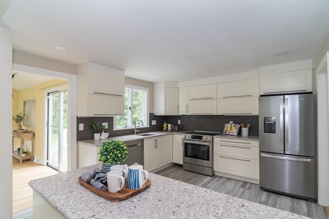 34 Brooks Rd, Wayland, MA 01778 - kitchen with stainless steel appliances, a sink, white cabinets, light wood finished floors, and decorative backsplash