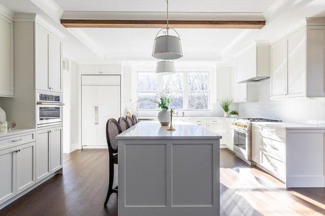 kitchen with premium appliances, dark wood-type flooring, light countertops, a center island, and beamed ceiling