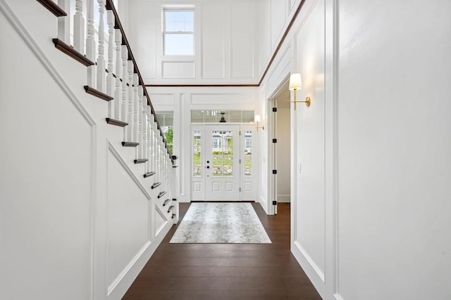 entryway with stairs, dark wood finished floors, and a decorative wall