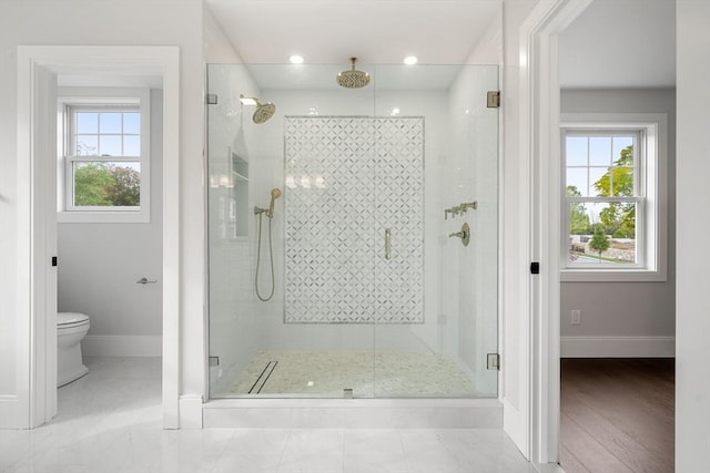 bathroom with a stall shower, a wealth of natural light, and baseboards