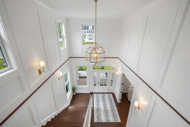 entryway featuring a notable chandelier, french doors, dark wood finished floors, and a decorative wall