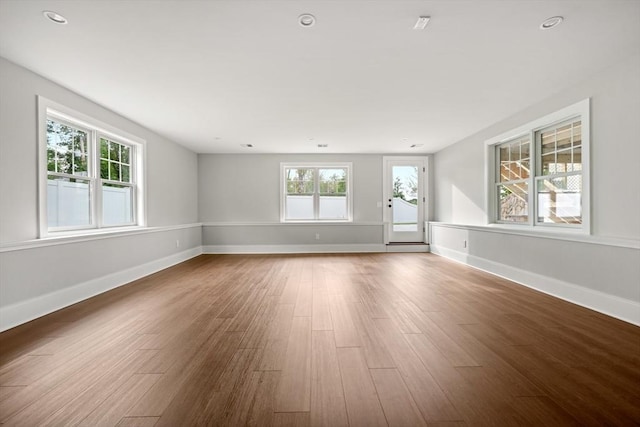 unfurnished living room with recessed lighting, wood finished floors, and baseboards