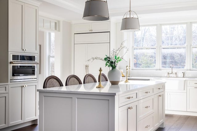 kitchen featuring dark wood-style flooring, a center island, hanging light fixtures, oven, and a sink