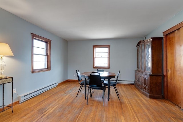 dining area featuring a baseboard heating unit, baseboards, and light wood finished floors