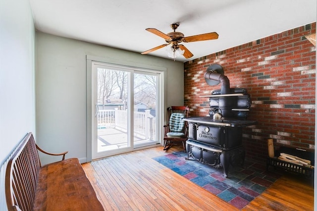 office featuring a wood stove, a ceiling fan, and wood-type flooring