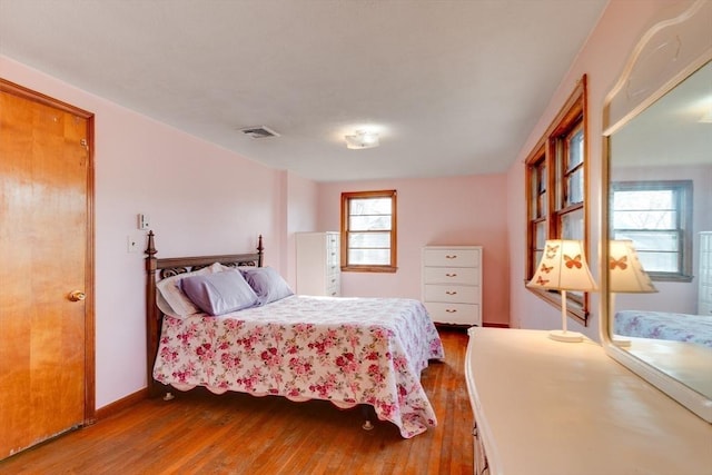 bedroom featuring visible vents, baseboards, and wood finished floors