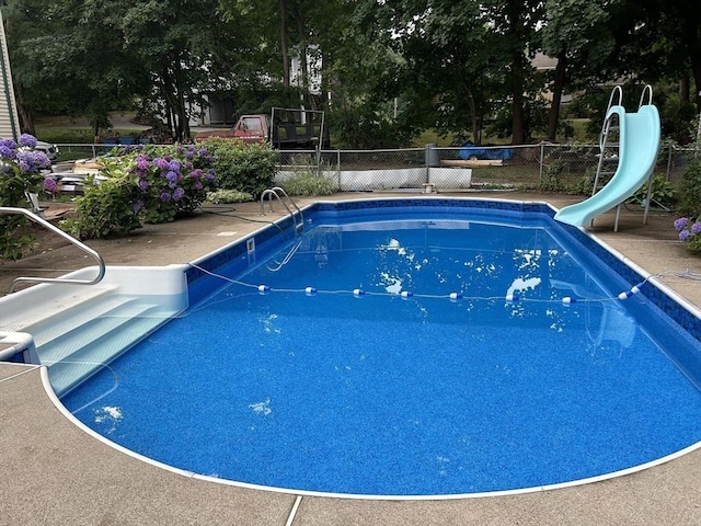 view of pool with a fenced in pool, a water slide, and fence