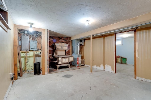 finished basement with electric panel, heating unit, and a textured ceiling