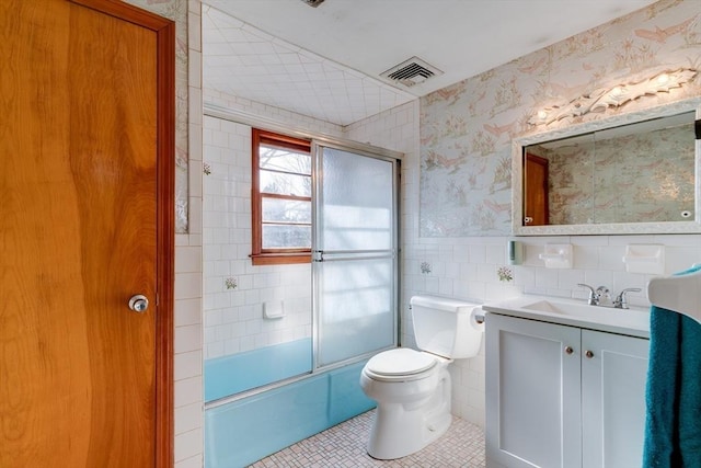 bathroom featuring visible vents, wallpapered walls, wainscoting, tile walls, and toilet