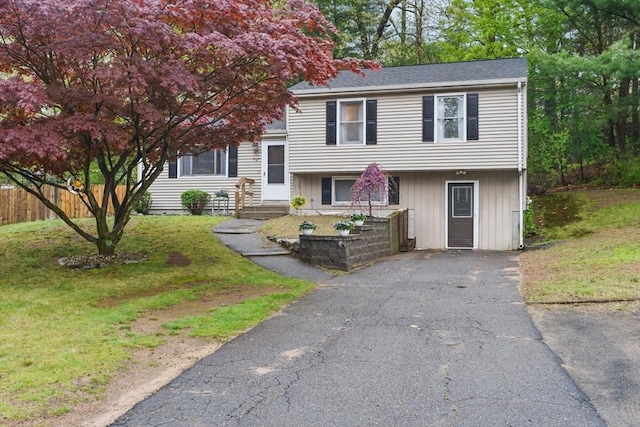 tri-level home with fence, a front lawn, and driveway